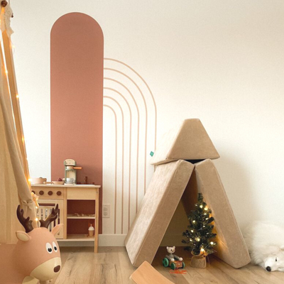 Picture of a playroom with a tall thin arch in a warm nut brown and half rainbow into the arch in warm beige wall decals 