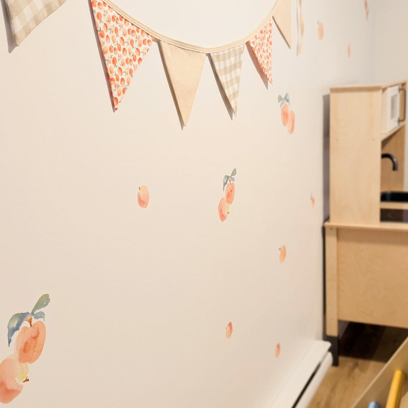 Fabric wall decals featuring charming peaches in a playroom, adding a fresh and fruity vibe. 