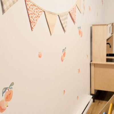 Fabric wall decals featuring charming peaches in a playroom, adding a fresh and fruity vibe. 