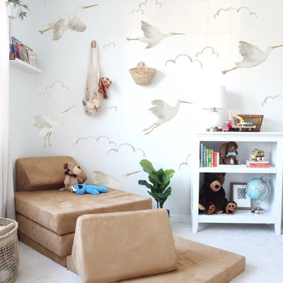 Fabric wall decals showcasing delicate storks and fluffy clouds in a play room. Ideal for creating a soft and dreamy atmosphere. 