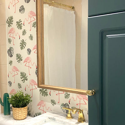 Bright pink flamingo wall decals in a bathroom surrounded by lush green leaves, designed for a playful and vibrant decor. The removable fabric decals are non-toxic, making them safe for any room.